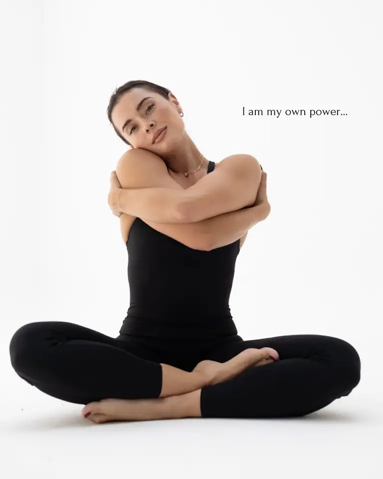 Woman seated cross-legged with arms wrapped around herself